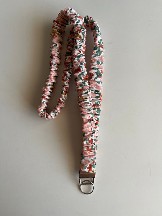Floral patterned lanyard with a metal clip on a light gray background