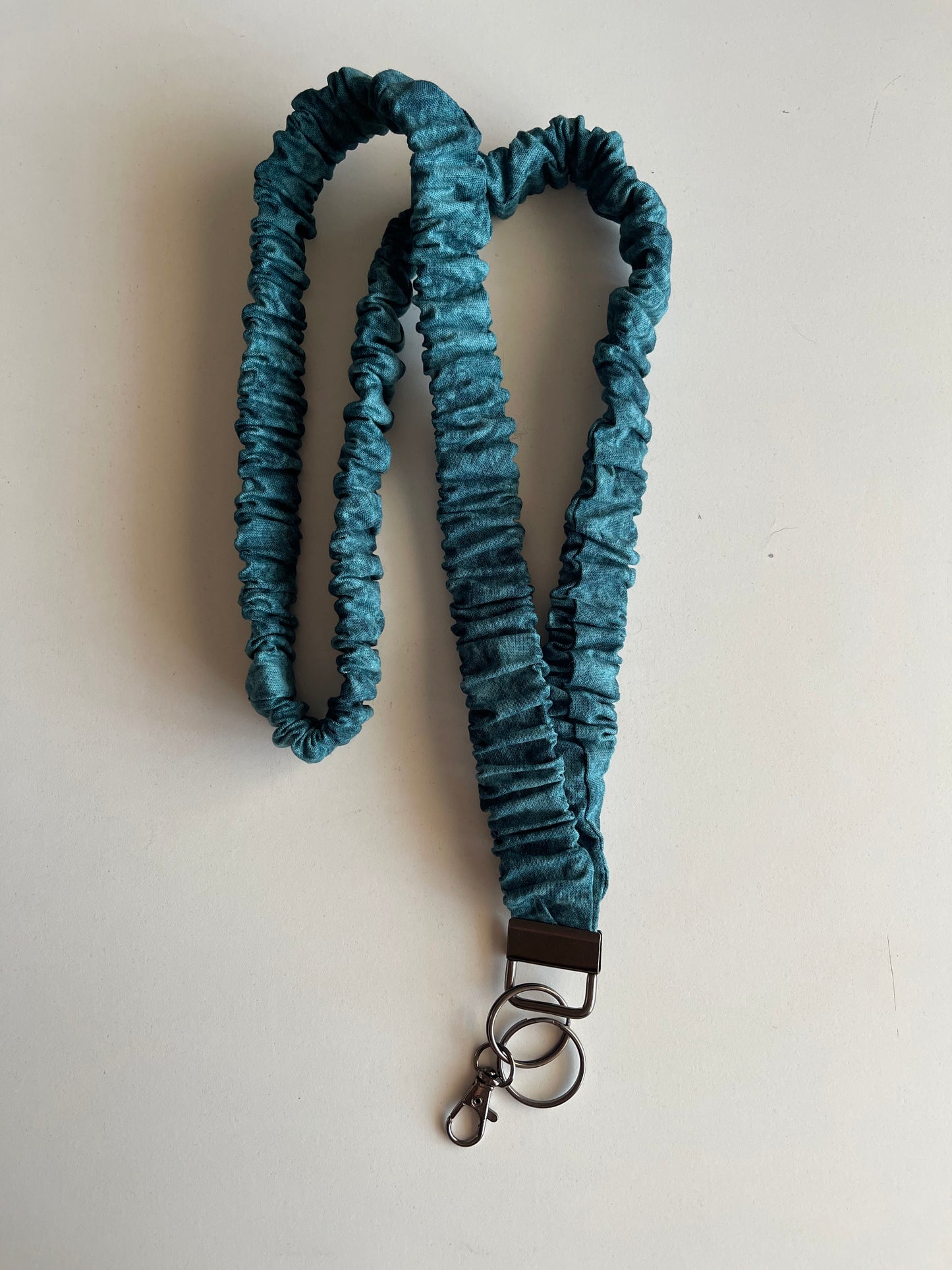 Turquoise wash lanyard with a metal clip on a white background