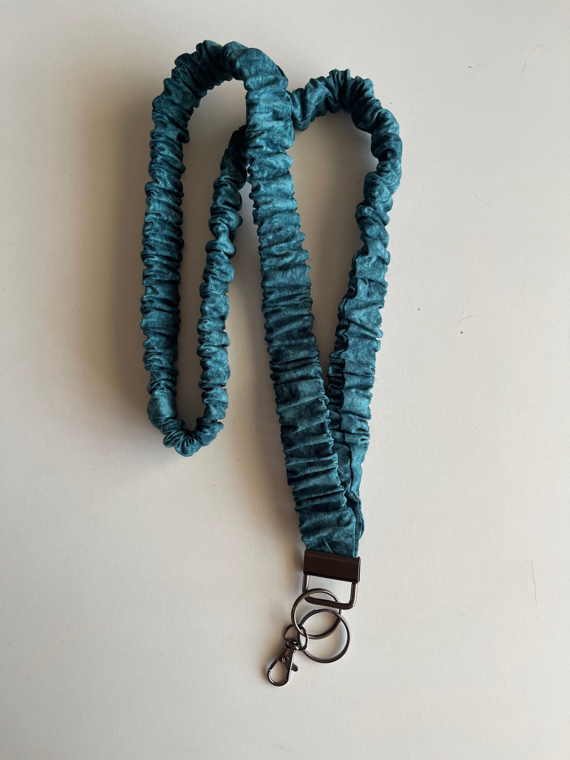Turquoise wash lanyard with a metal clip on a white background