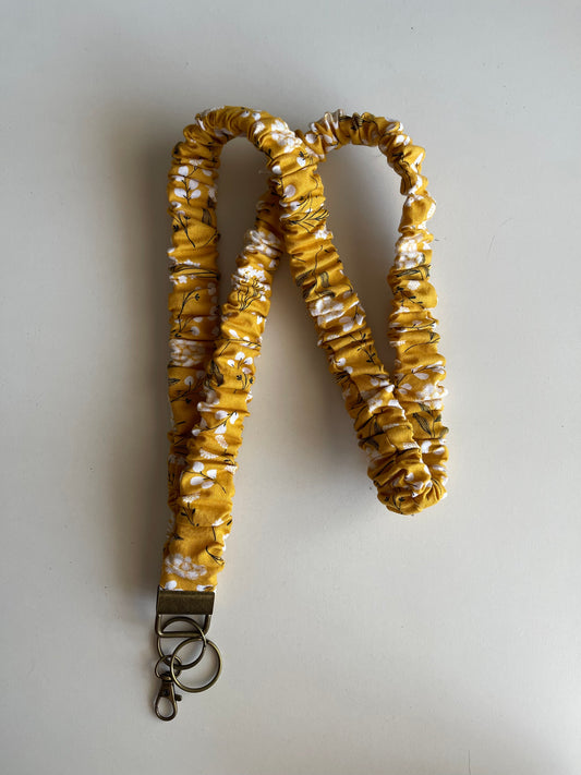Yellow and white patterned lanyard with a key ring on a light gray background